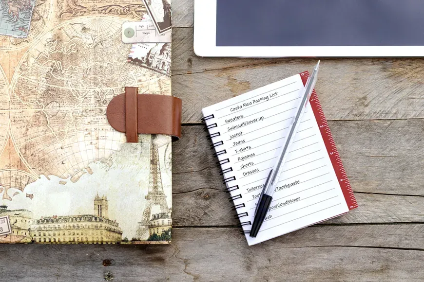 packing list written in a notebook on table.